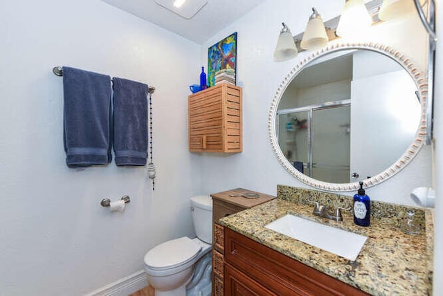 bathroom with vanity, a shower with door, and toilet
