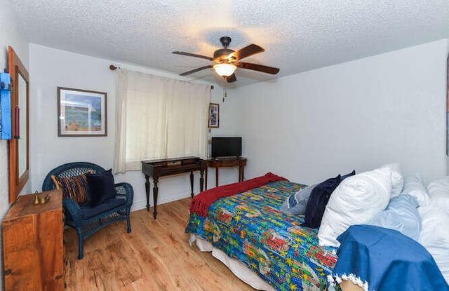 bedroom with ceiling fan, wood finished floors, and a textured ceiling