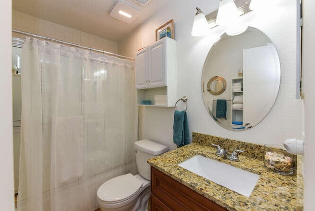 bathroom with toilet, vanity, and curtained shower