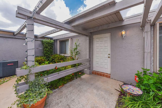 property entrance with central AC and stucco siding
