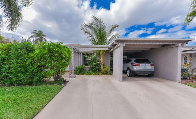 view of front facade with driveway, a carport, and stucco siding