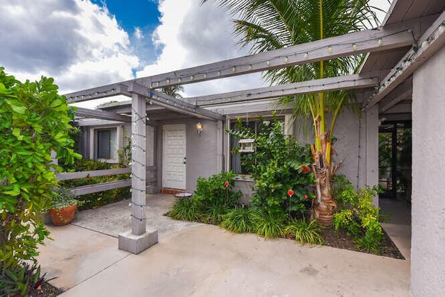 entrance to property with stucco siding and a patio