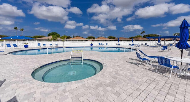 pool with a community hot tub, a patio area, and fence