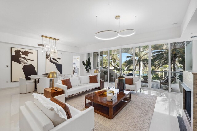 tiled living area featuring visible vents, a notable chandelier, and a high end fireplace