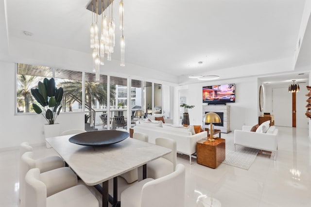 living room featuring a notable chandelier, a lit fireplace, and tile patterned floors