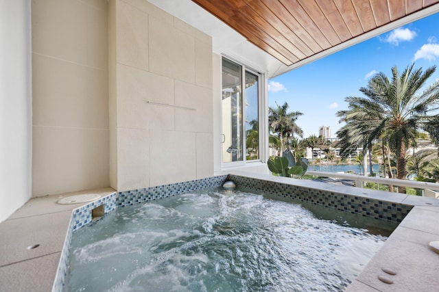 view of swimming pool with a water view and an in ground hot tub