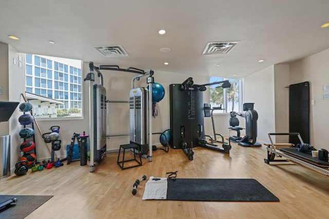 exercise area featuring baseboards, wood finished floors, visible vents, and recessed lighting