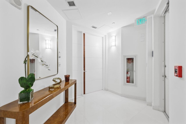 hall featuring tile patterned floors, baseboards, and visible vents