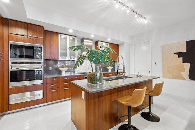 kitchen featuring a sink, a warming drawer, stainless steel oven, modern cabinets, and brown cabinetry