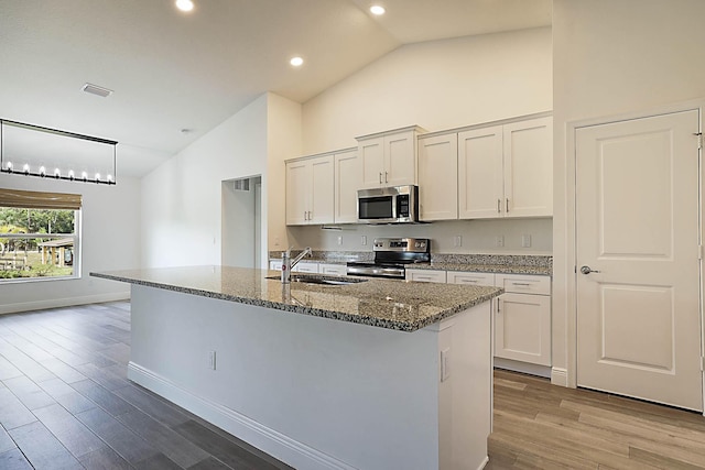 17854 N 71st Ln N, The Acreage, FL 33470 - kitchen featuring appliances with stainless steel finishes, a sink, high vaulted ceiling, wood finished floors, and stone counters
