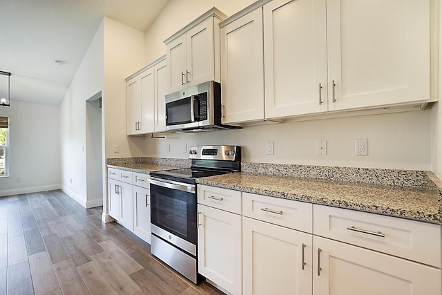 17854 N 71st Ln N, The Acreage, FL 33470 - kitchen featuring stainless steel appliances, light stone countertops, wood finished floors, and baseboards