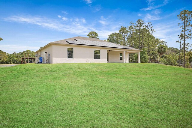 17854 N 71st Ln N, The Acreage, FL 33470 - rear view of property with stucco siding, a yard, and roof mounted solar panels