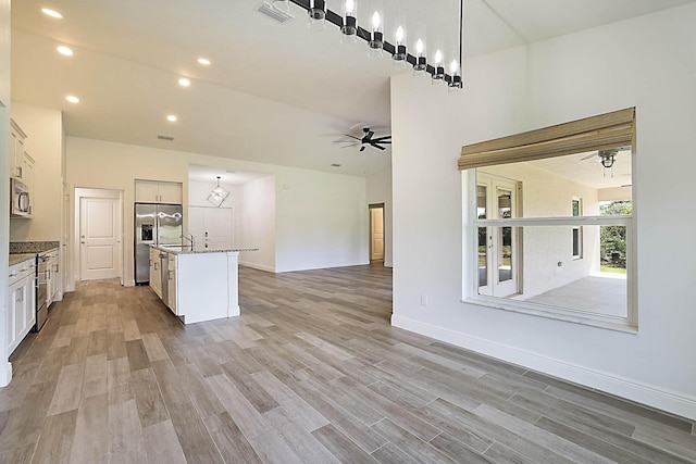 17854 N 71st Ln N, The Acreage, FL 33470 - kitchen featuring appliances with stainless steel finishes, open floor plan, light wood finished floors, a ceiling fan, and hanging light fixtures