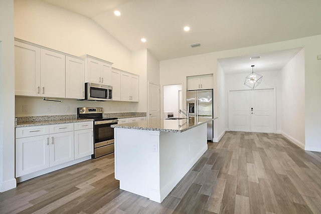 17854 N 71st Ln N, The Acreage, FL 33470 - kitchen featuring stainless steel appliances, wood finished floors, light stone countertops, an island with sink, and recessed lighting