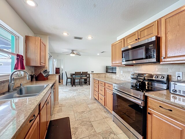178 Via De La Reina, Merritt Island, FL 32953 - kitchen with decorative backsplash, stainless steel appliances, stone tile flooring, ceiling fan, and a sink