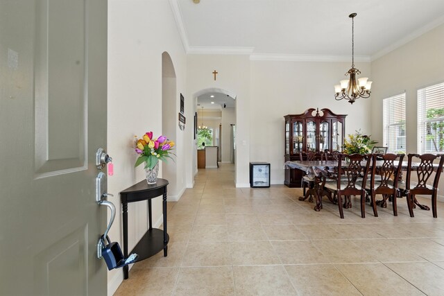 707 Cresta Cir, West Palm Beach, FL 33413 - dining area featuring arched walkways, a notable chandelier, ornamental molding, and light tile patterned floors