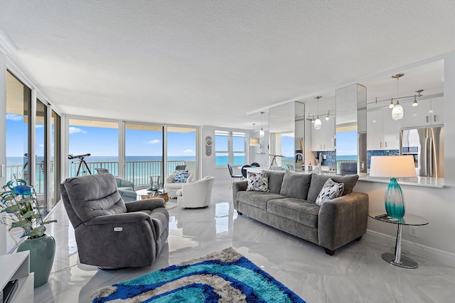 living room with a water view, a textured ceiling, baseboards, and marble finish floor