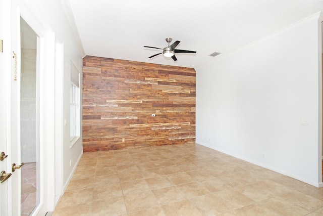 empty room with wooden walls, visible vents, ornamental molding, an accent wall, and ceiling fan