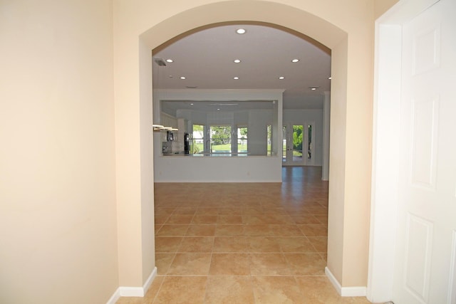 hallway with baseboards, arched walkways, light tile patterned flooring, and recessed lighting