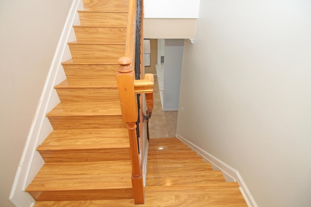 staircase featuring wood finished floors and baseboards