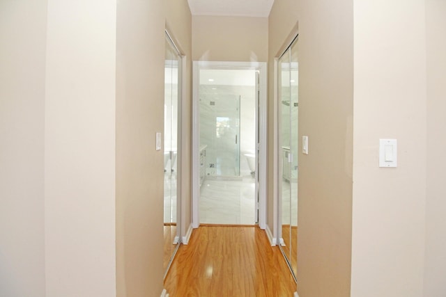 corridor featuring light wood finished floors and baseboards