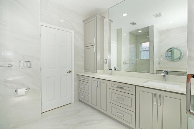 bathroom with marble finish floor, a sink, visible vents, and double vanity