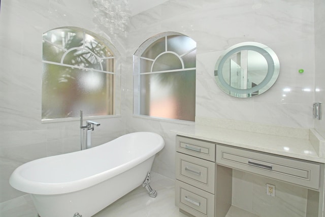 bathroom featuring vanity, a freestanding bath, marble finish floor, and tile walls
