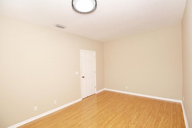 spare room with baseboards, visible vents, and light wood finished floors