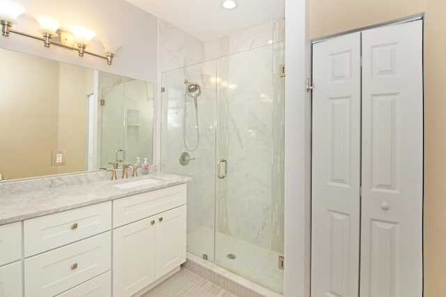 full bathroom with recessed lighting, vanity, a marble finish shower, and a closet