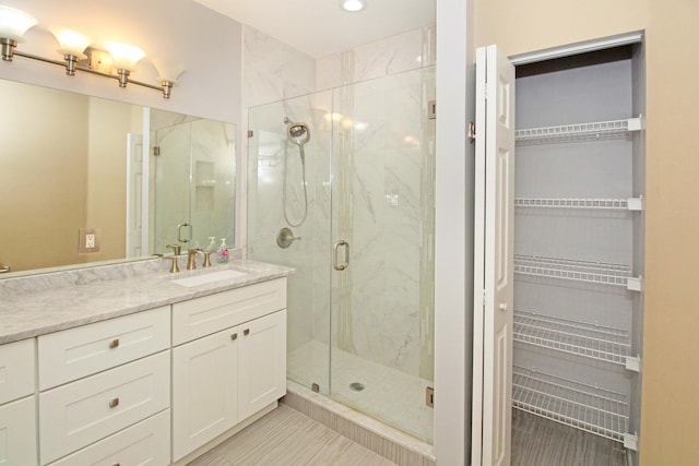 full bath featuring a marble finish shower, a spacious closet, vanity, tile patterned flooring, and recessed lighting