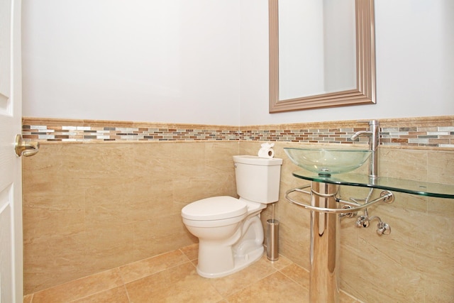 bathroom featuring tile walls, tile patterned flooring, a wainscoted wall, and toilet