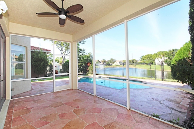 unfurnished sunroom with a water view and ceiling fan