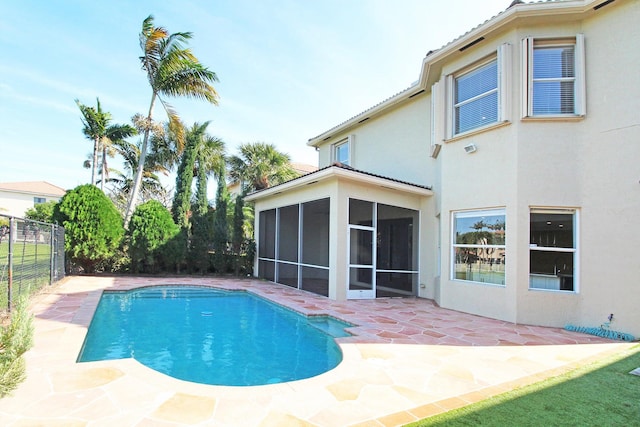 outdoor pool featuring fence, a sunroom, and a patio