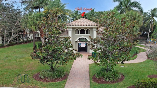 view of front facade featuring a tiled roof, a front lawn, and stucco siding