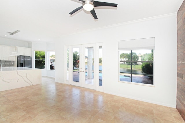 unfurnished living room featuring a water view, light tile patterned floors, ceiling fan, french doors, and ornamental molding