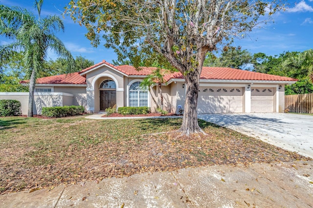 mediterranean / spanish house featuring driveway, a tile roof, a garage, fence, and stucco siding
