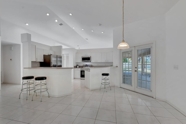 kitchen featuring white cabinets, stainless steel appliances, a peninsula, a kitchen bar, and visible vents