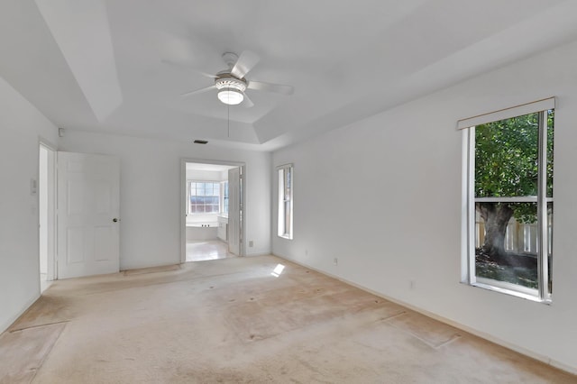 carpeted spare room featuring ceiling fan, a tray ceiling, and visible vents