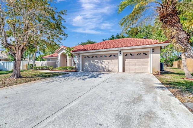 mediterranean / spanish home featuring fence, stucco siding, concrete driveway, an attached garage, and a tile roof