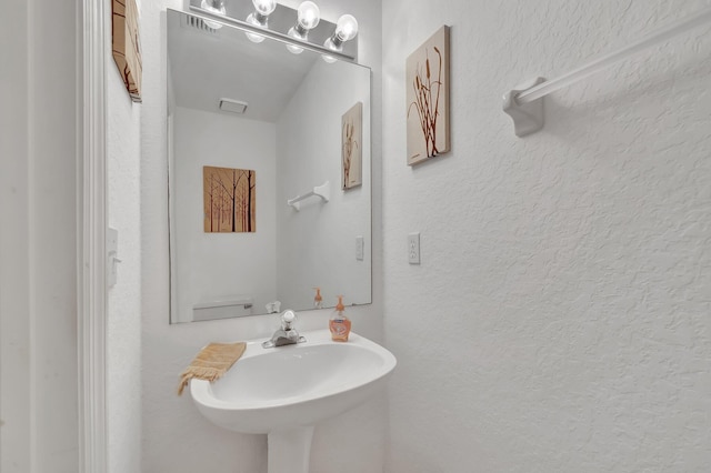 bathroom with visible vents, a sink, and a textured wall
