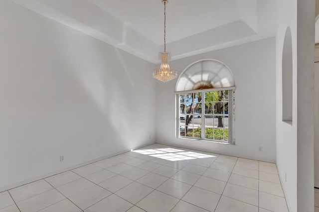 unfurnished room featuring arched walkways, light tile patterned floors, and a tray ceiling
