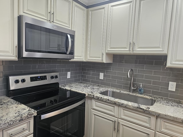 kitchen with light stone countertops, stainless steel appliances, a sink, and tasteful backsplash