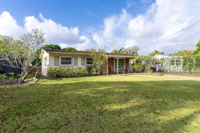 rear view of house with a lawn and fence