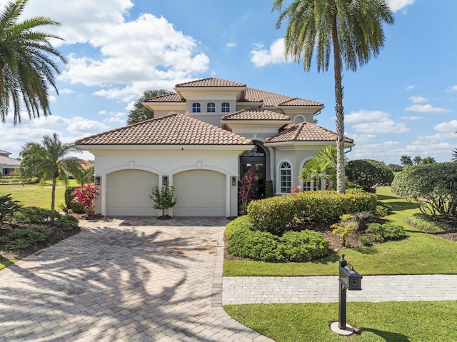 mediterranean / spanish house featuring a garage, stucco siding, driveway, and a front yard