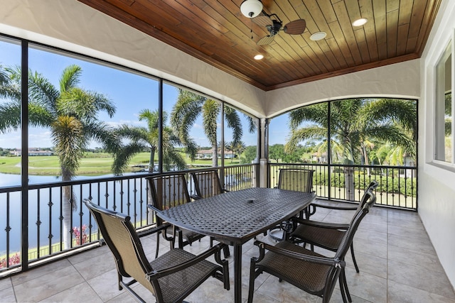 sunroom with a healthy amount of sunlight, a water view, and ceiling fan