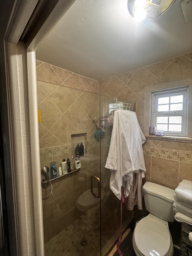 bathroom featuring tile walls, a stall shower, and toilet