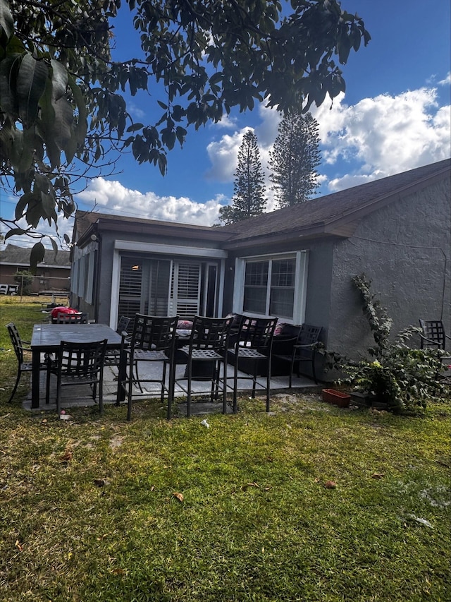 rear view of property featuring a patio, outdoor lounge area, a yard, and stucco siding