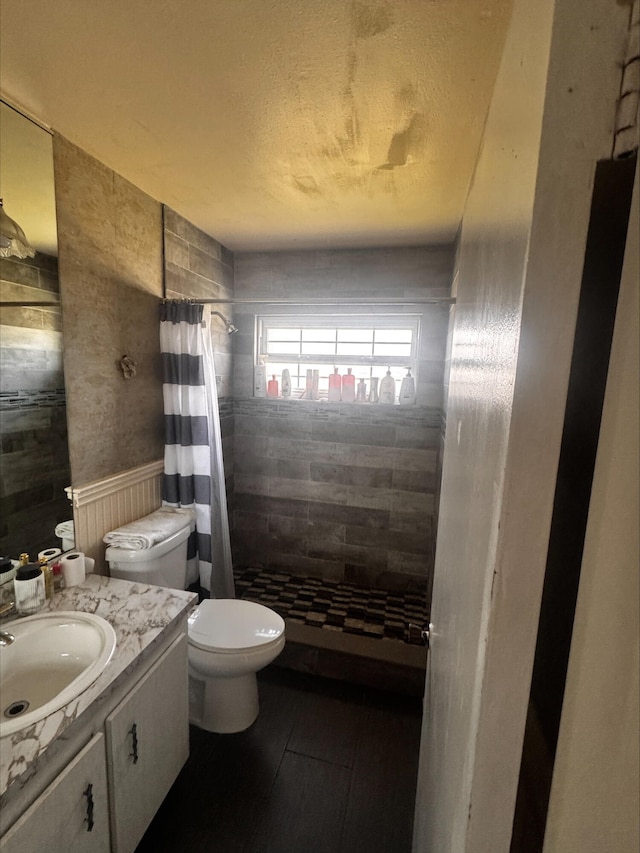 full bath with wainscoting, a shower stall, toilet, and vanity
