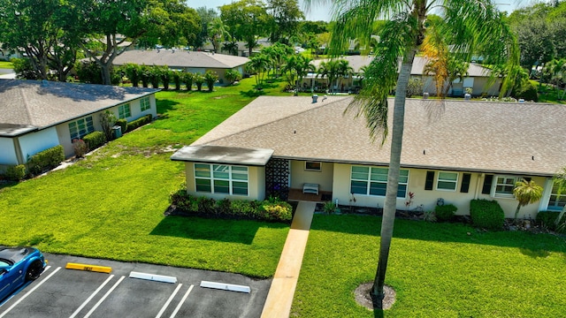 955 Circle A Dr Unit A, Delray Beach, FL 33445 - view of front facade featuring uncovered parking, stucco siding, a front lawn, and roof with shingles