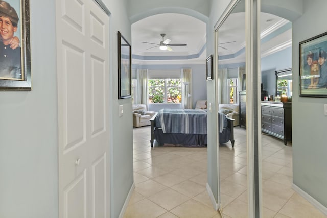 bedroom with ornamental molding, arched walkways, light tile patterned floors, and a tray ceiling